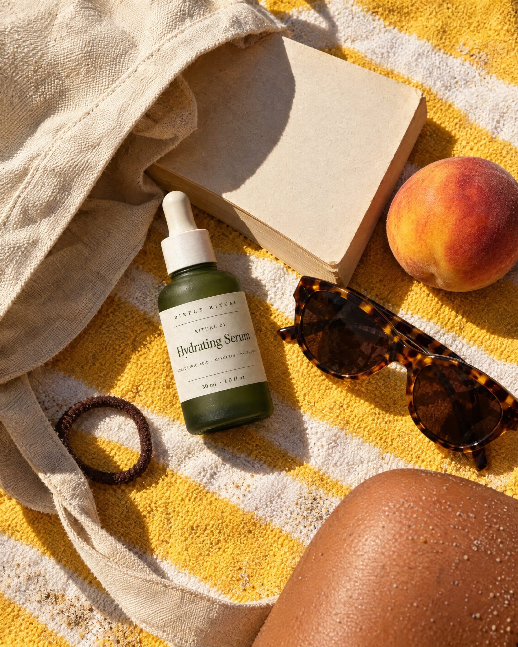 The Direct Ritual serum in a beach bag on a striped towel